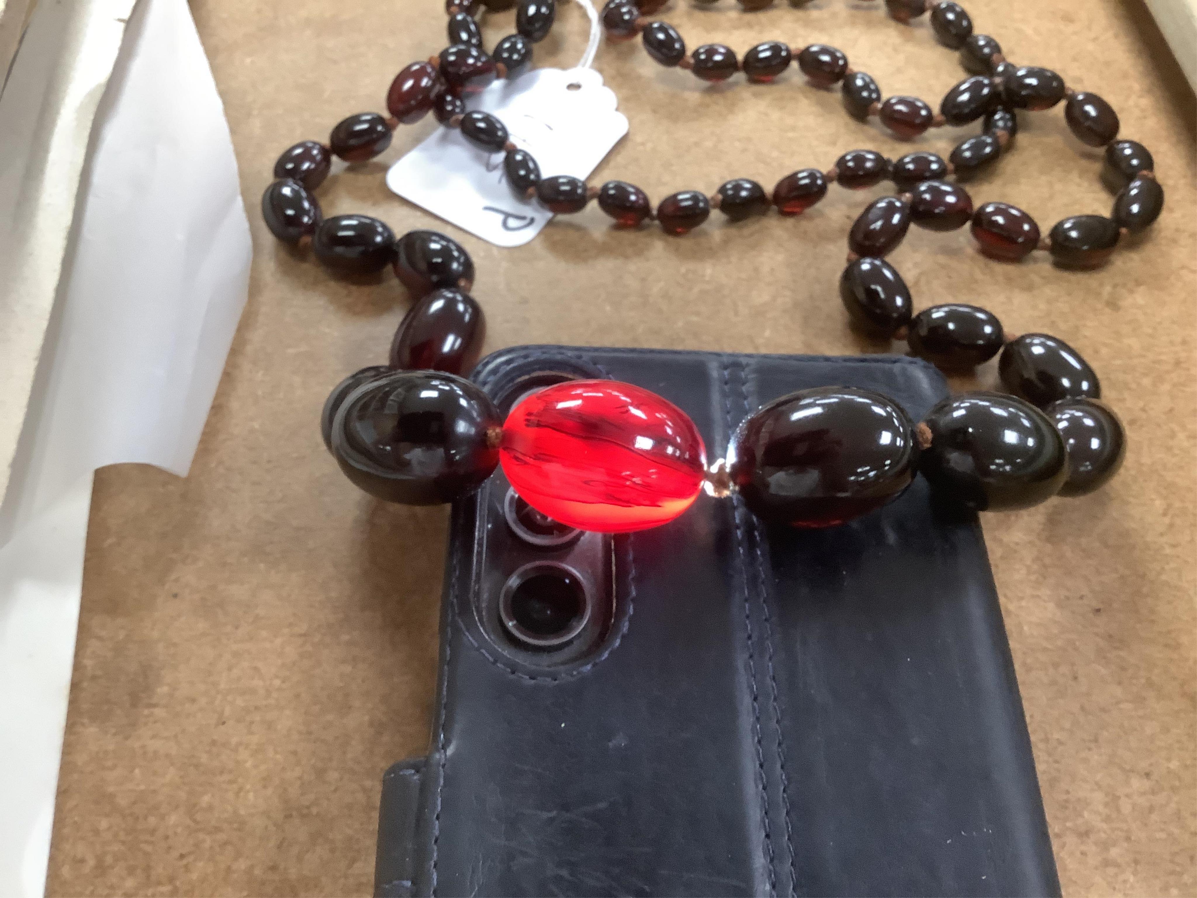 A single strand graduated simulated oval dark cherry amber bead necklace, 110cm, gross weight 90 grams.